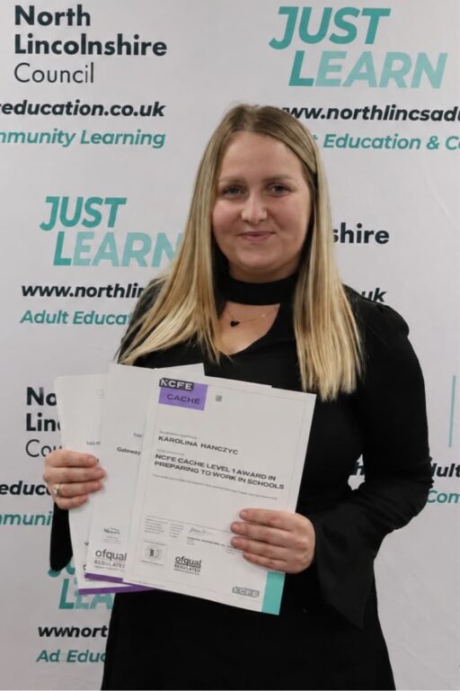 Learner dressed in black smiling and holding certificates